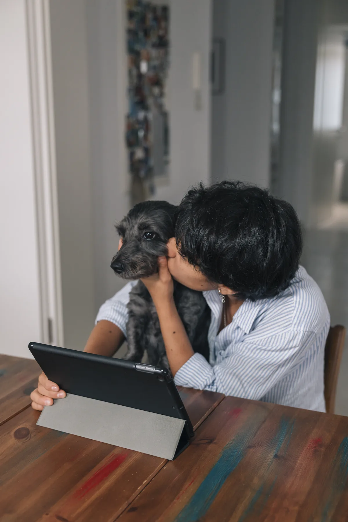 Una persona abraza a su perro mientras usa una tablet
